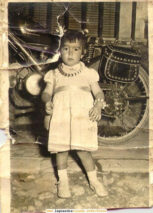 Niña posando delante de una moto. Años 60